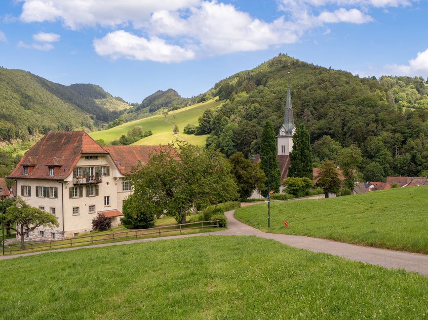 Charming Swiss village with traditional architecture, lush green hills, and a picturesque church.