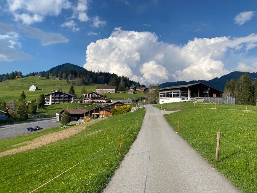 Quaint Swiss village nestled in the Alps with lush greenery and stunning cloudscape.
